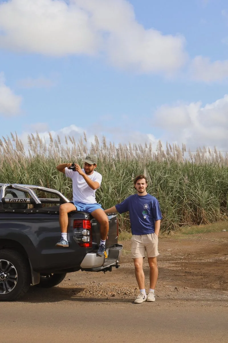 Deux amis près d'un pick-up devant un champ de cannes