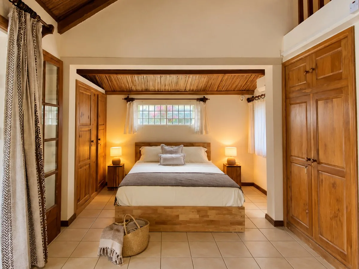 Chambre de guesthouse sous charpente en bois, lumière chaude et terrasse ouverte