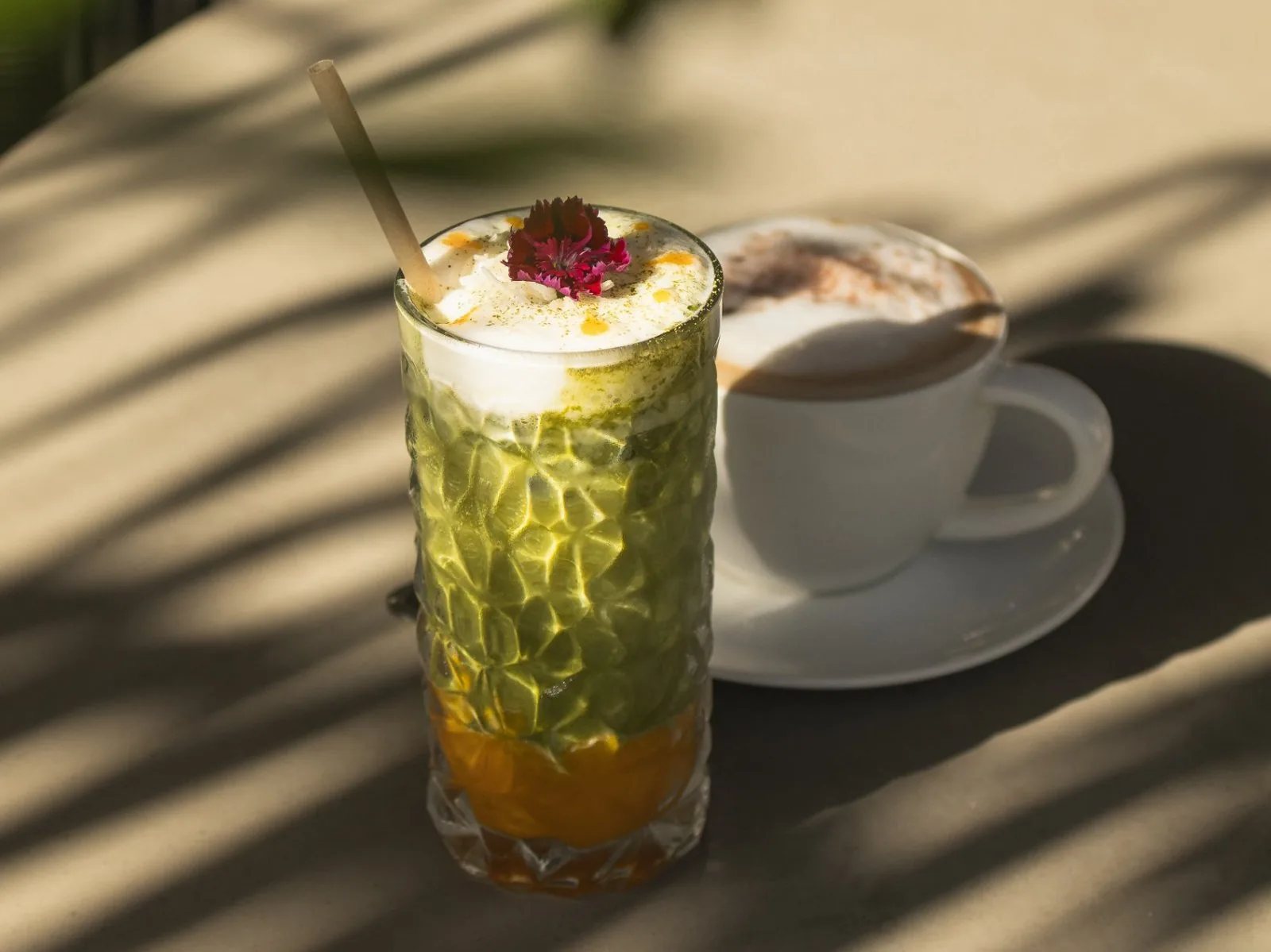 Cocktail au matcha et cappuccino au soleil, sous les ombres de palmes